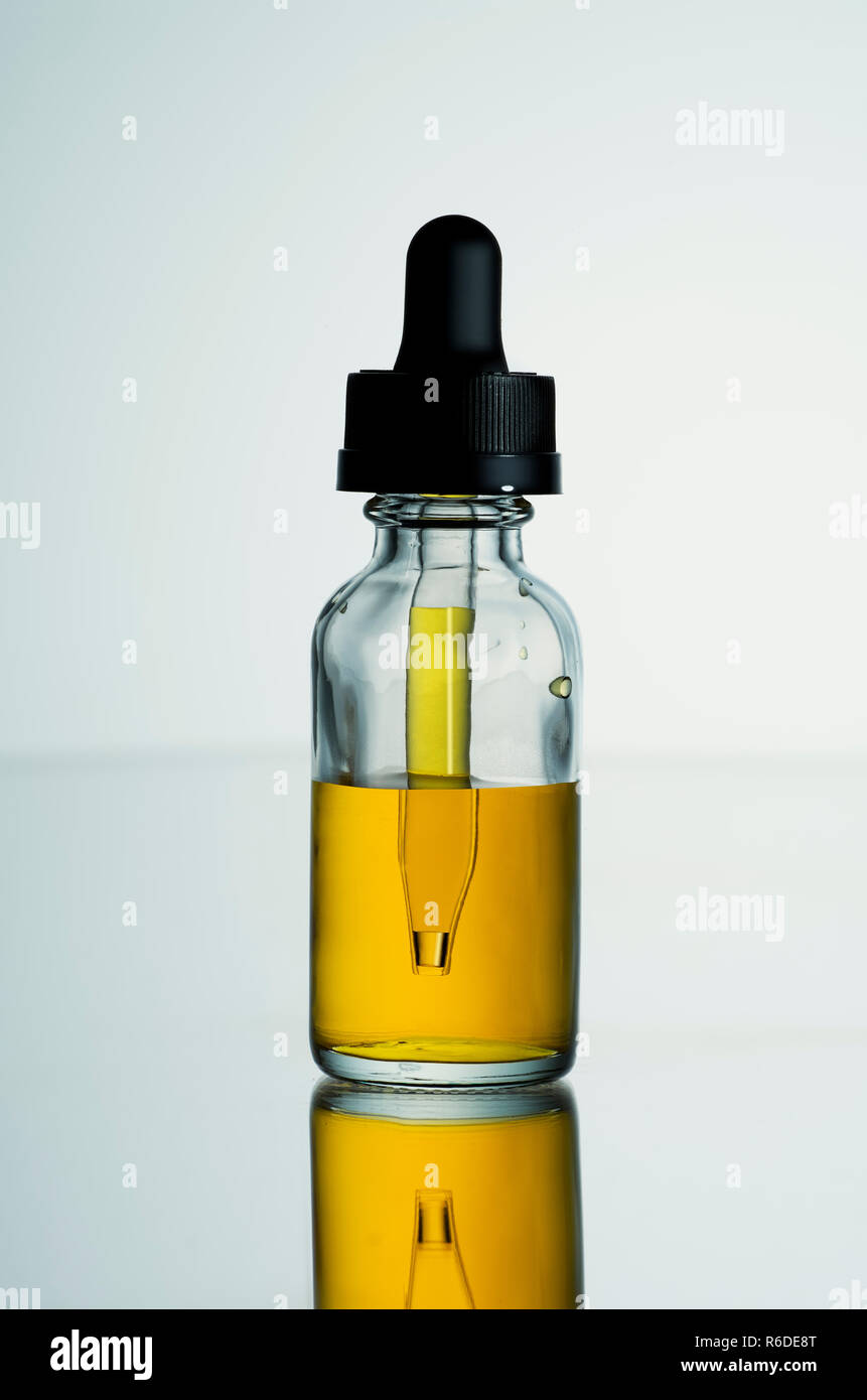 Close up image of small jar with screw top dropper containing golden liquid Stock Photo