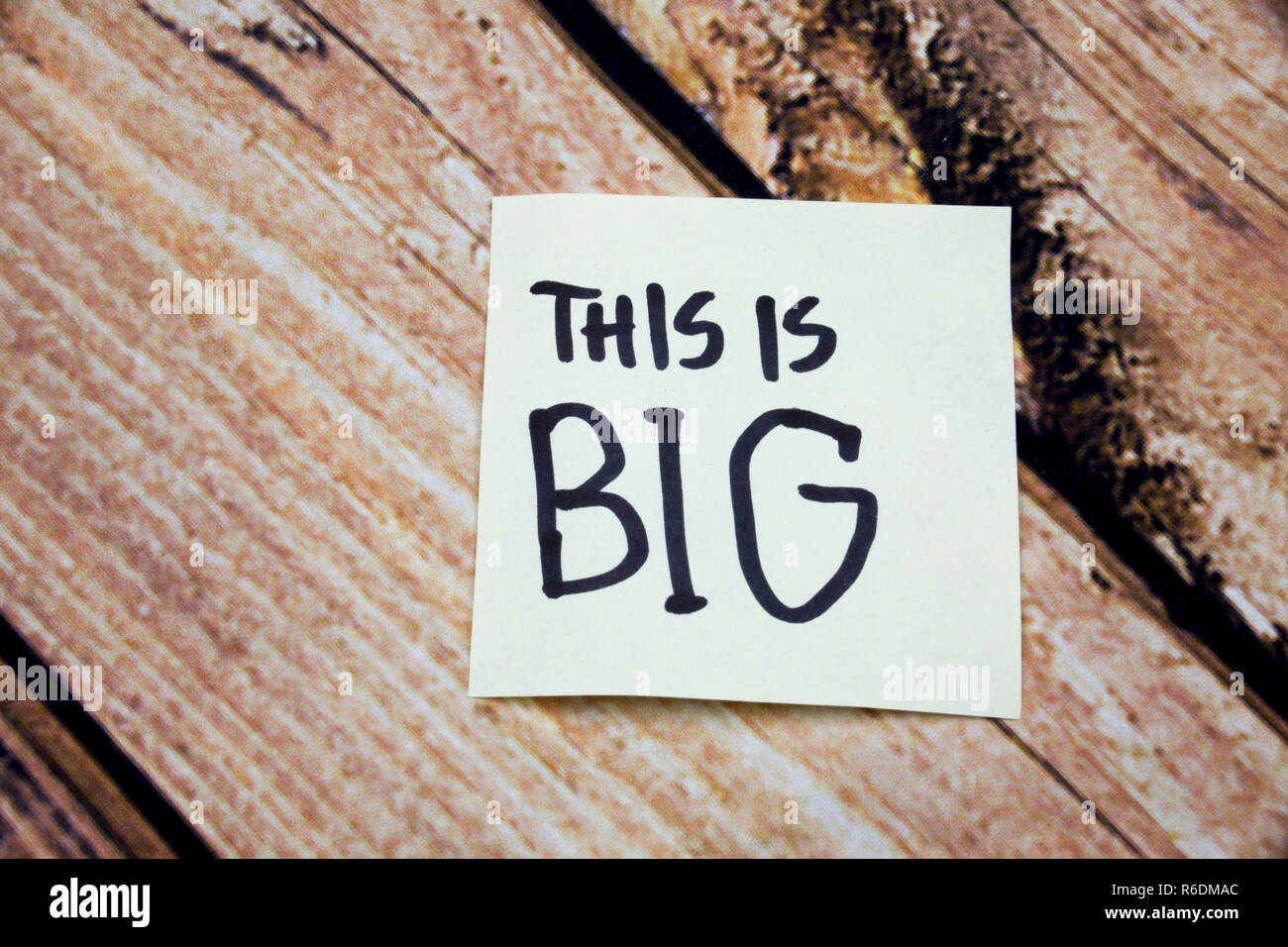 Sticky note on the wooden background and text concept, this is big