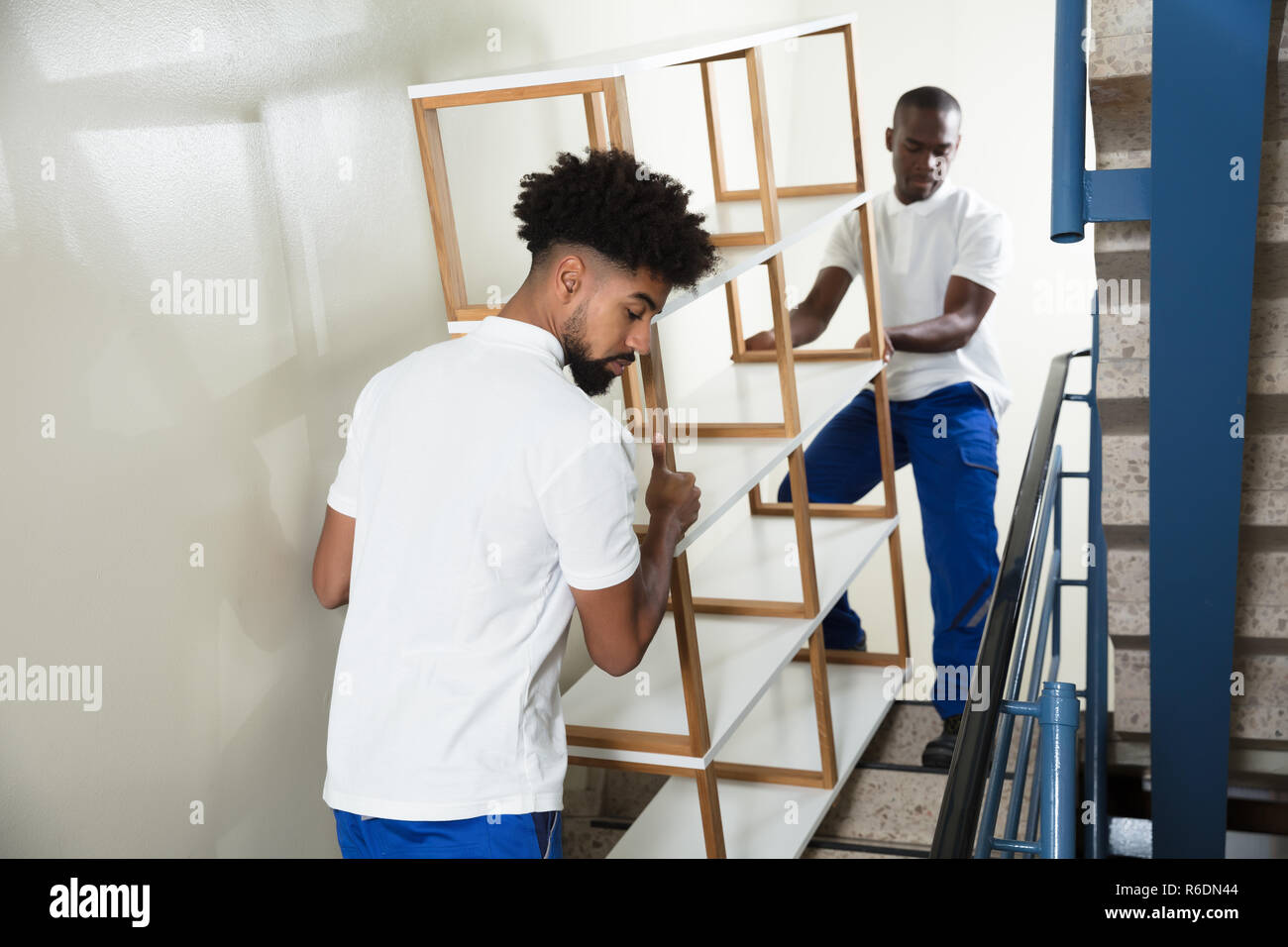 Two Male Movers Carrying The Empty Shelf At Home Stock Photo