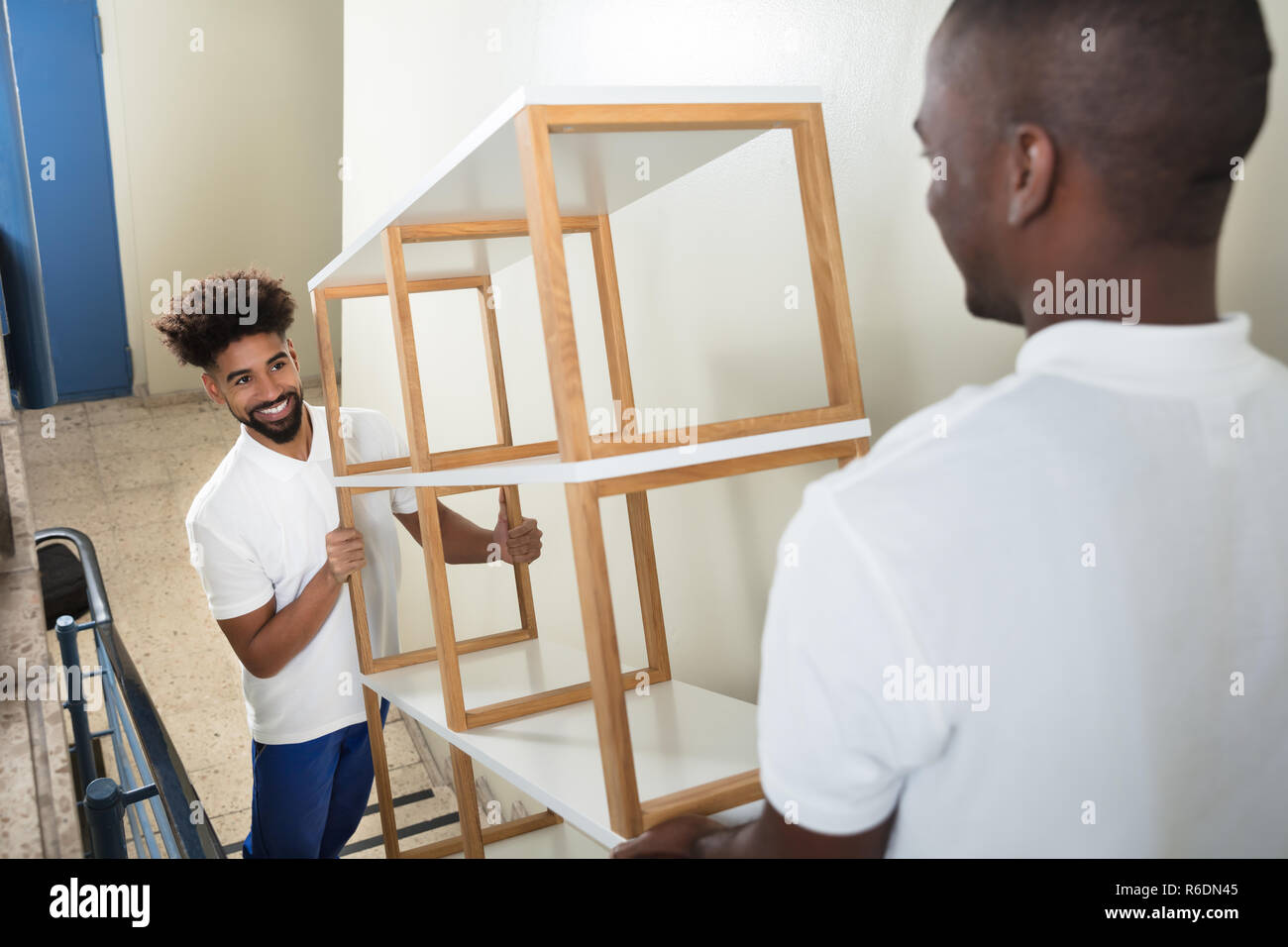Two Male Movers Carrying The Empty Shelf At Home Stock Photo