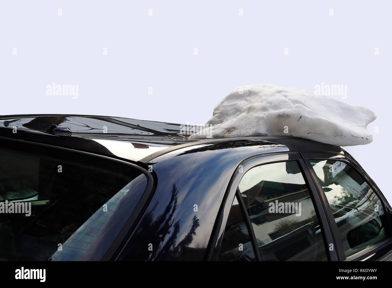 a roof avalanche severely damaged a black car on the roof. damaged by a roof avalanche on a car Stock Photo