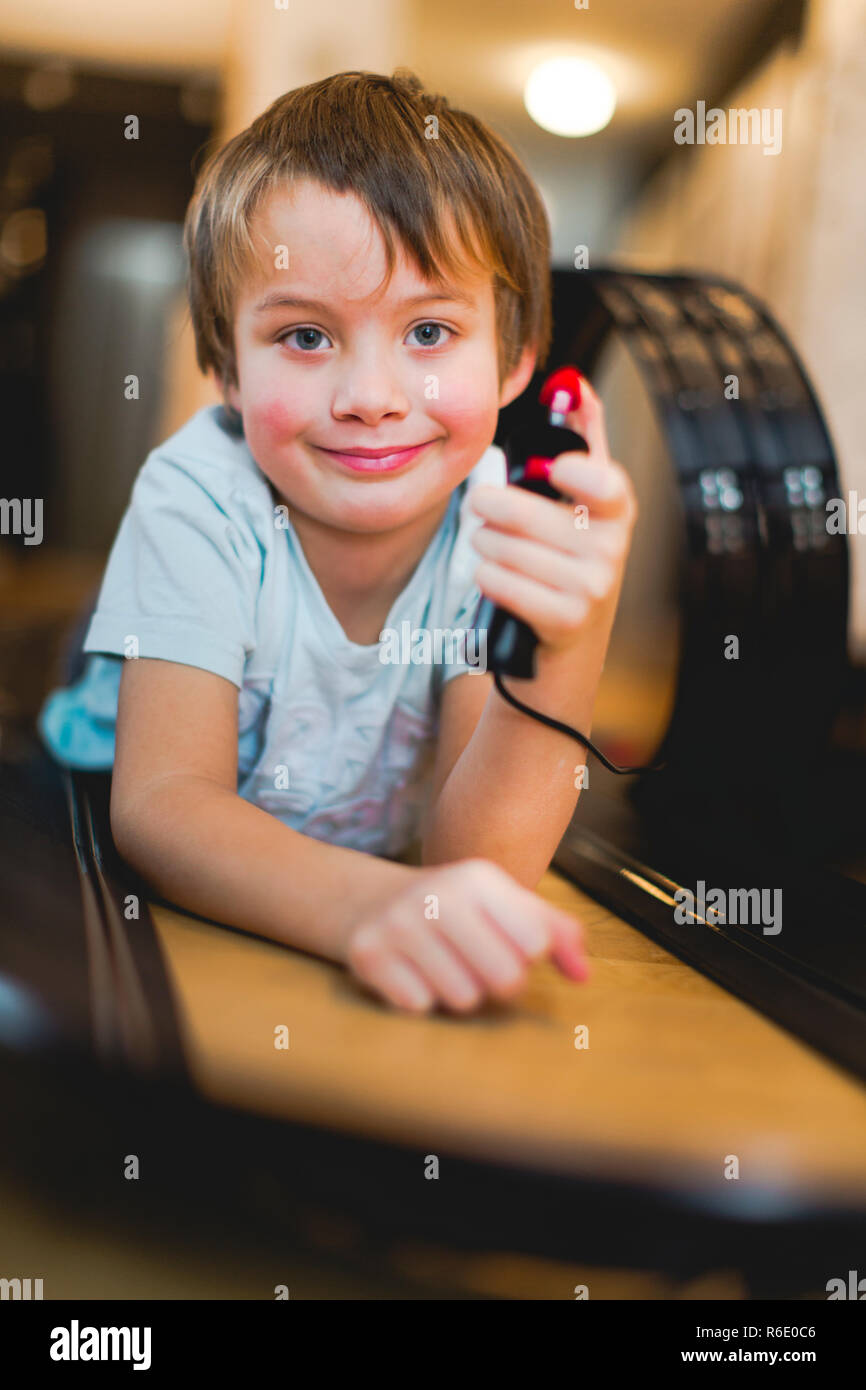 5 year old boy is playing with slot car model racing track Stock Photo