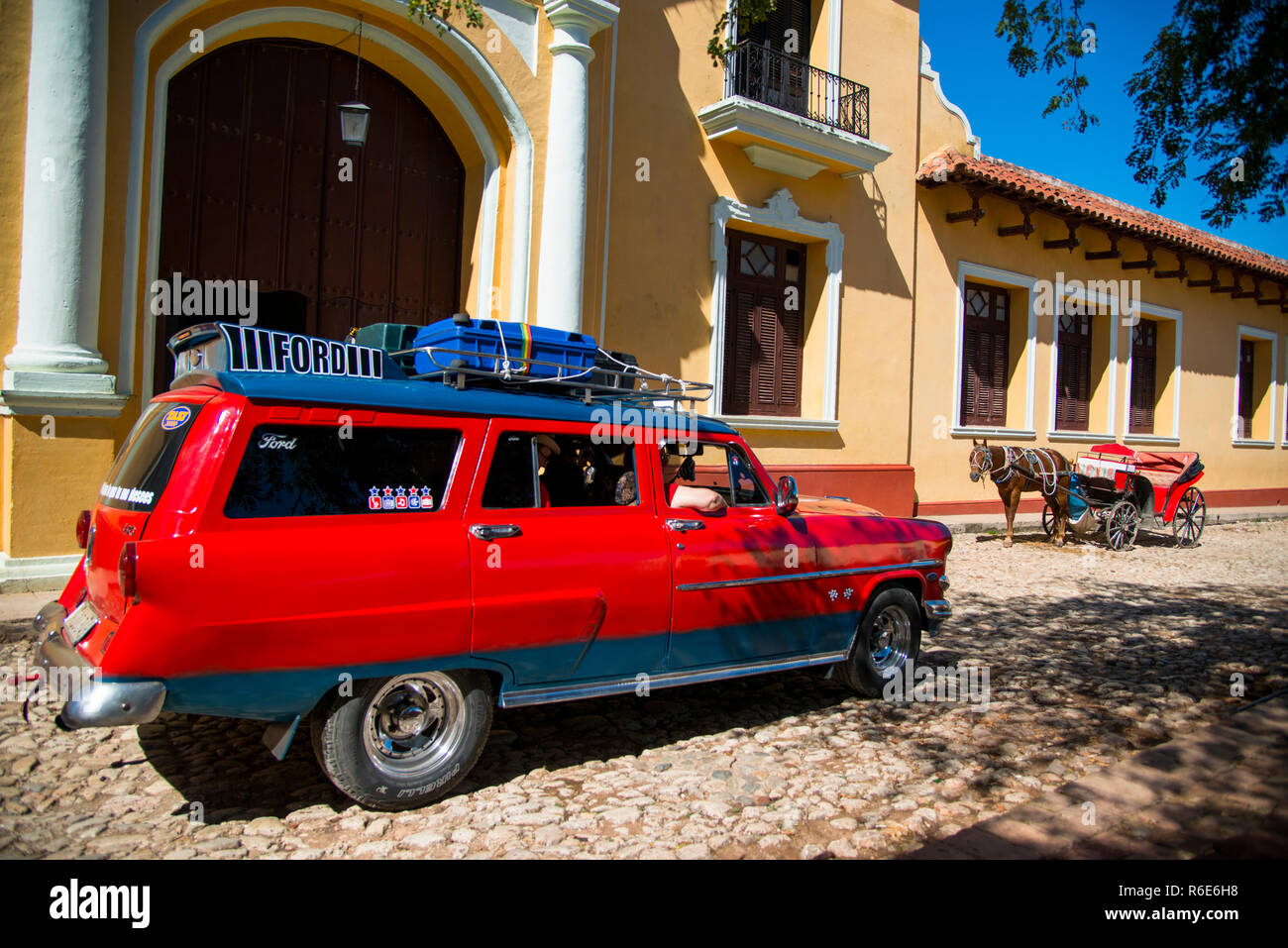 Ford station wagon in Trinidad, Cuba. Hose and carriage for tourists in the background. Stock Photo