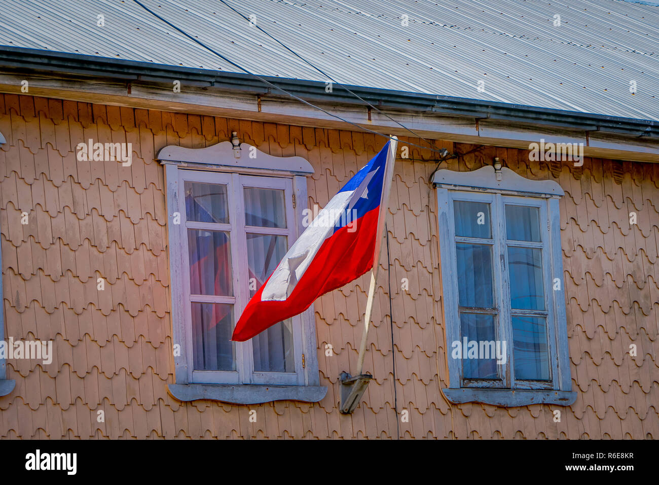 Outdoor view of wooden building with a Chilean flag waving in Chiloe ...