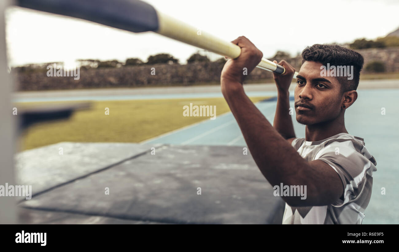 Man setting up a pole at a height for high jump. Close up of a man resetting the height of the bar for high jump. Stock Photo