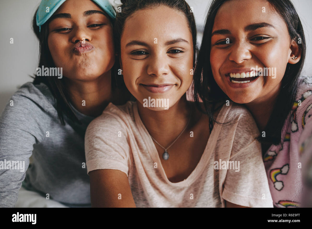 Three young girls sitting together posing for a selfie during a sleepover. Girls having a good time during a sleepover. Stock Photo