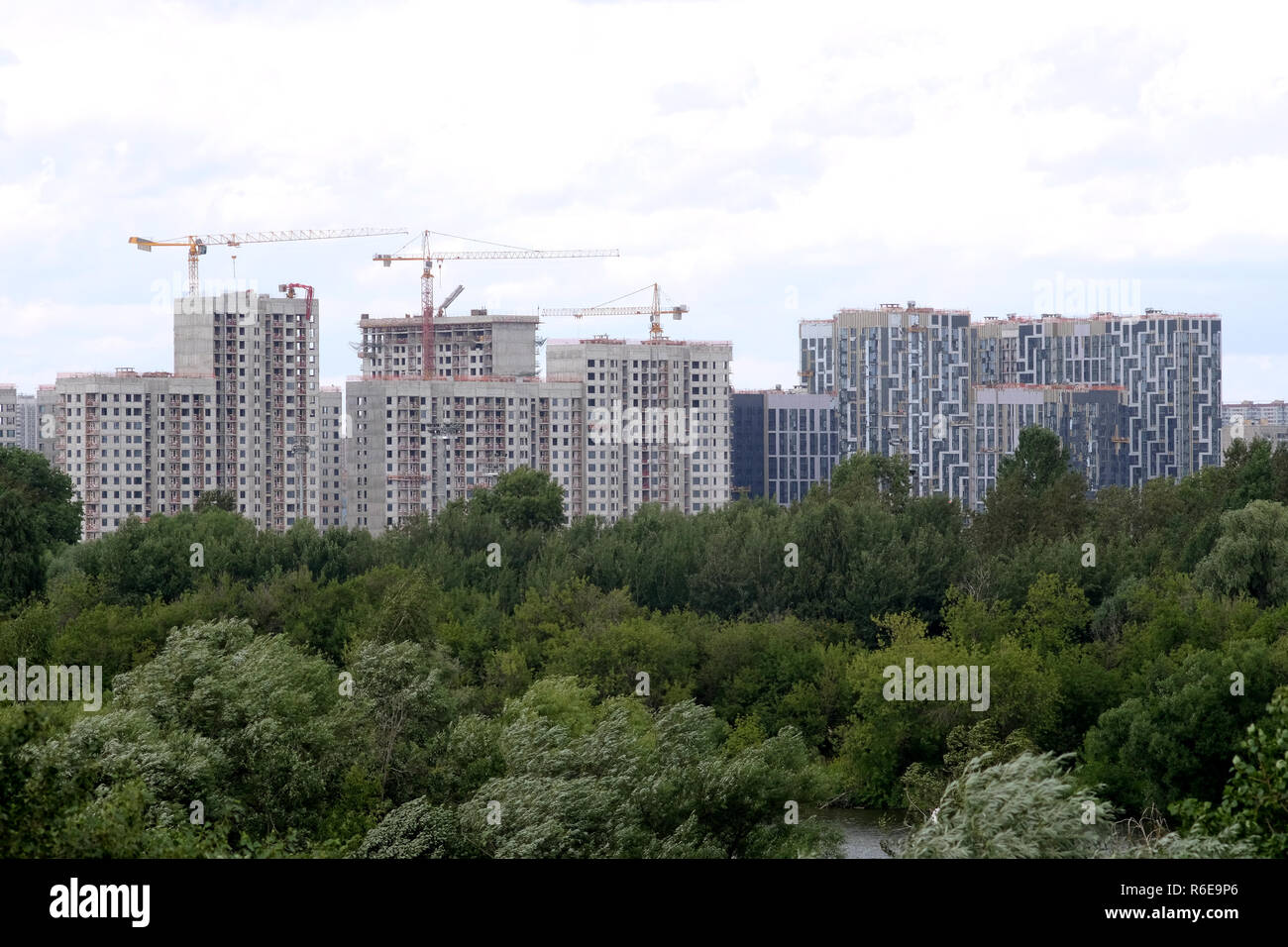 City construction. Landscape with cranes and new block of flats construction in new green ecological district sky with white clouds in summer day Stock Photo