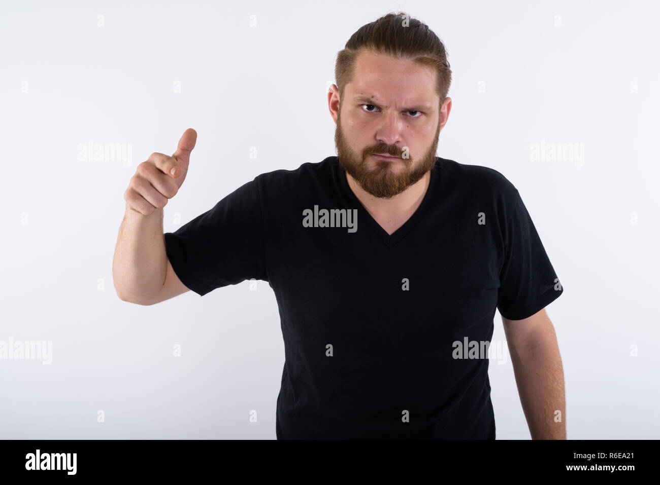 Studio shot of young angry bearded man pointing at camera with h Stock Photo