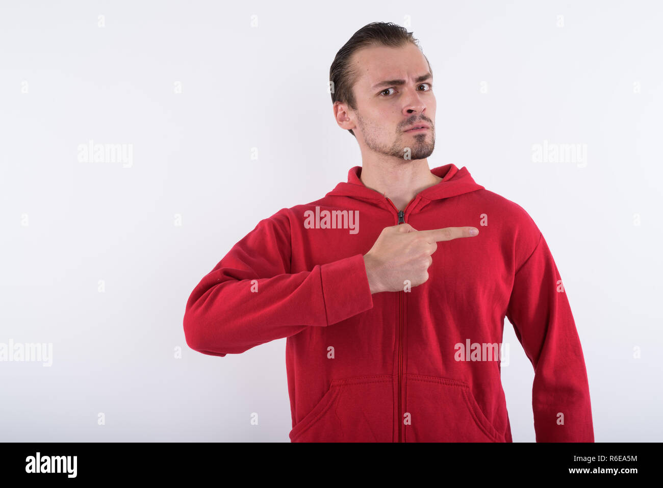 Studio shot of young angry bearded man pointing to the side agai Stock Photo