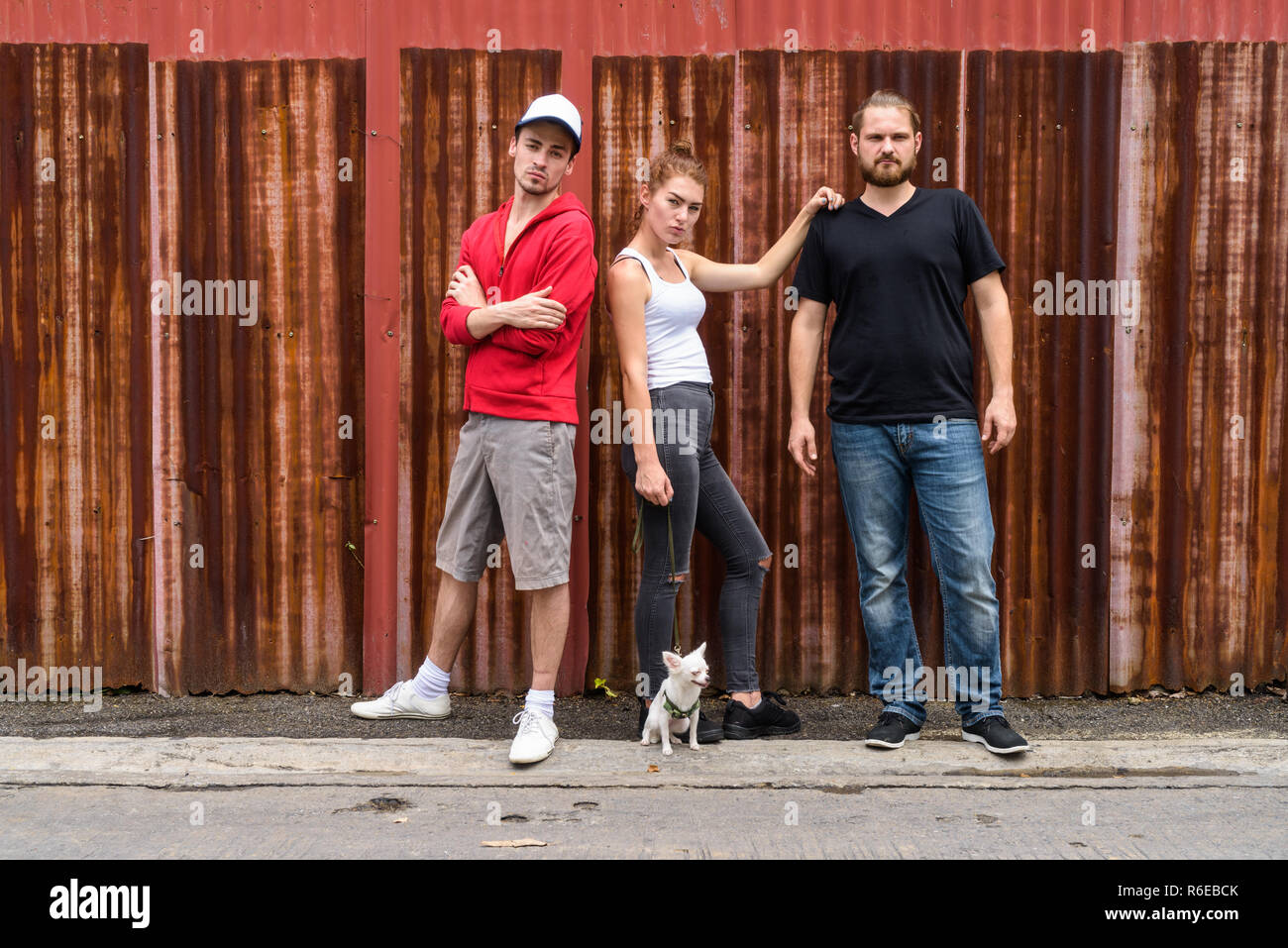 Group of friends standing against old rusty sheet wall with woma Stock Photo