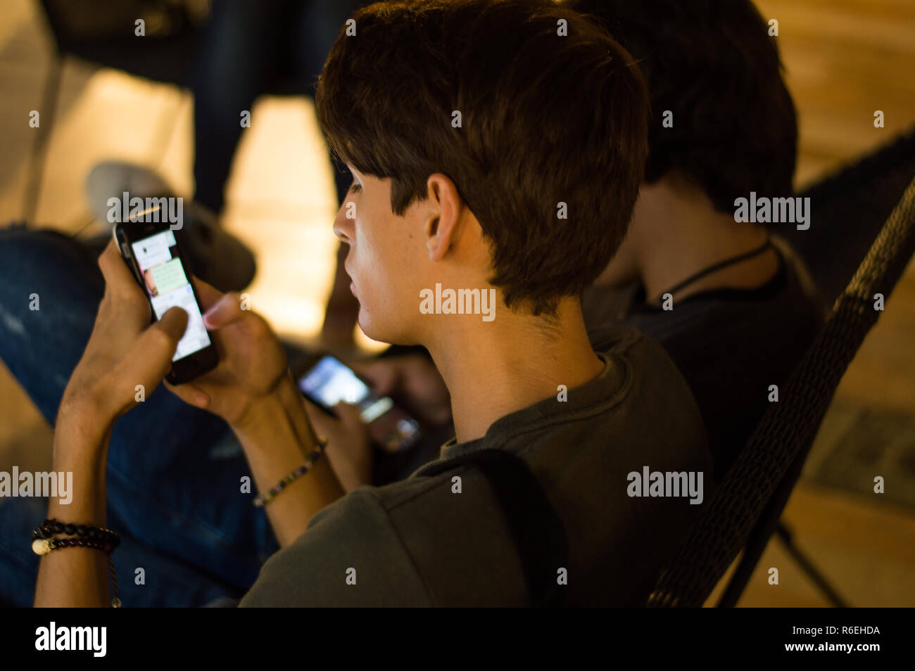 Engrossed teens scrolling through their mobile phones, ignoring each other Stock Photo