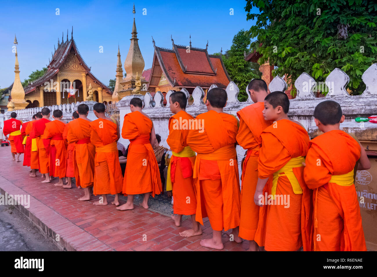 Young Monks At The Alms Giving Ceremony In Front Of The Wat Sene, Luang Prabang, Laos Stock Photo