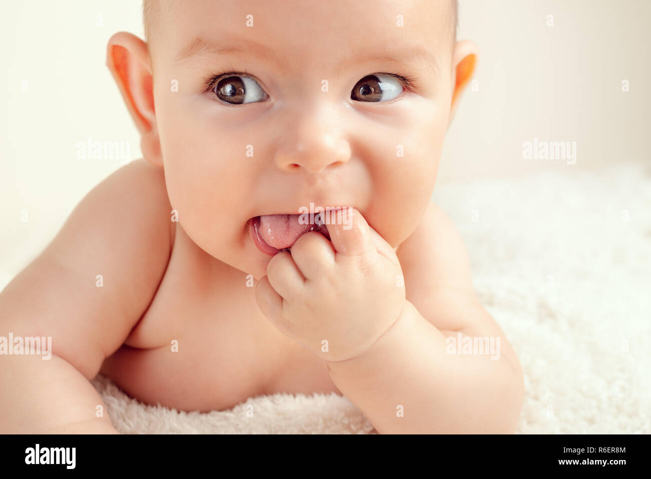 Small cute funny baby infant teething with face expression hands and