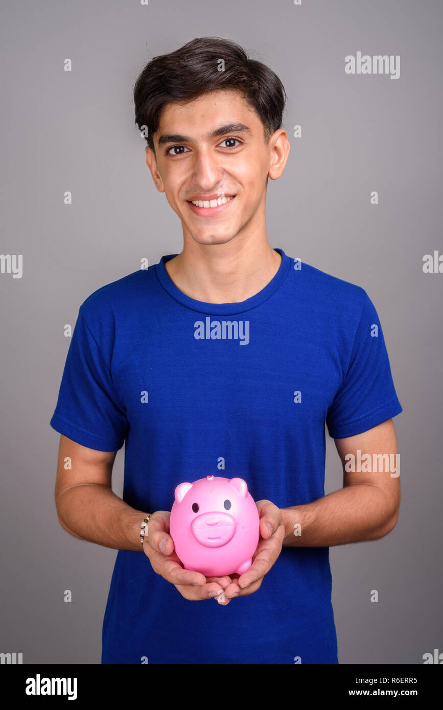 Young handsome Persian teenage boy holding piggy bank Stock Photo - Alamy