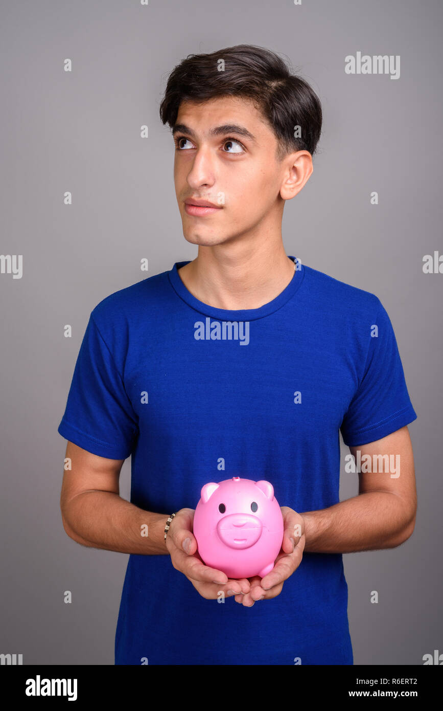 Young handsome Persian teenage boy holding piggy bank Stock Photo - Alamy