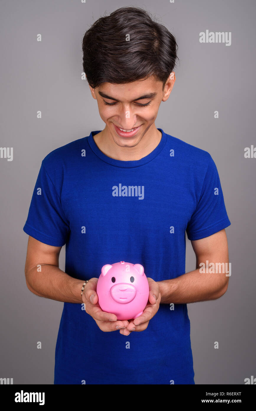 Young handsome Persian teenage boy holding piggy bank Stock Photo - Alamy