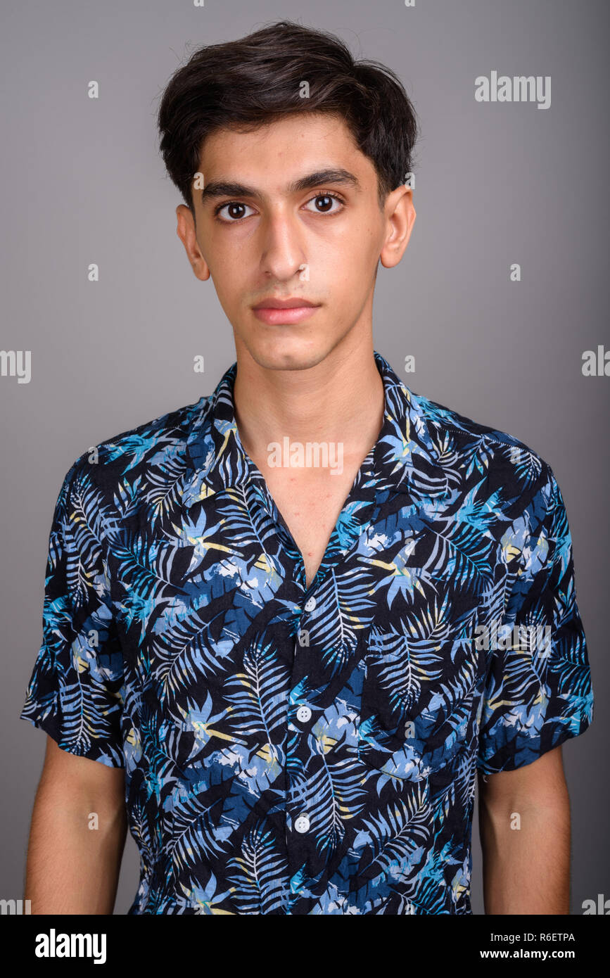 Young handsome Persian teenage boy wearing Hawaiian shirt agains Stock Photo