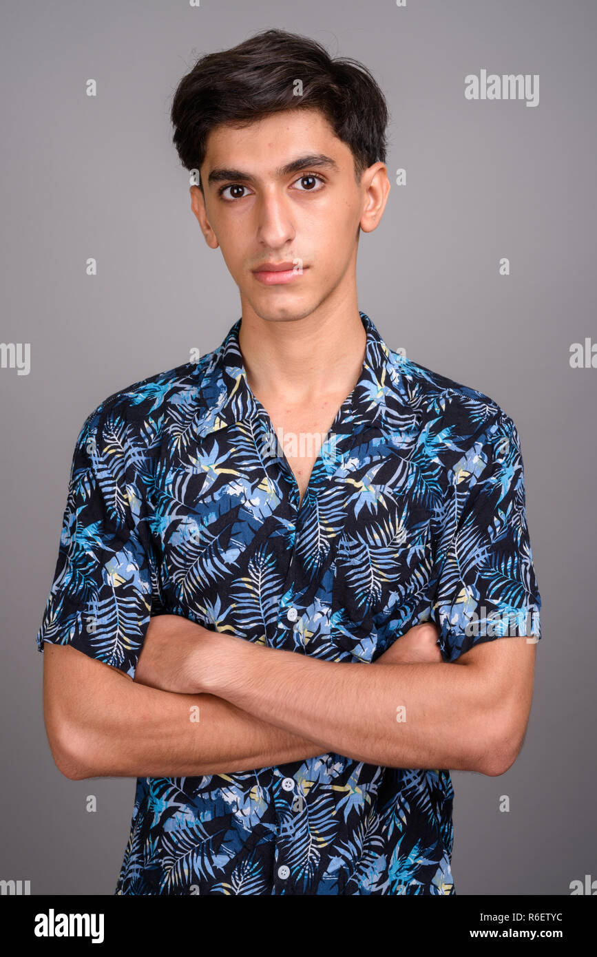 Young handsome Persian teenage boy wearing Hawaiian shirt agains Stock Photo
