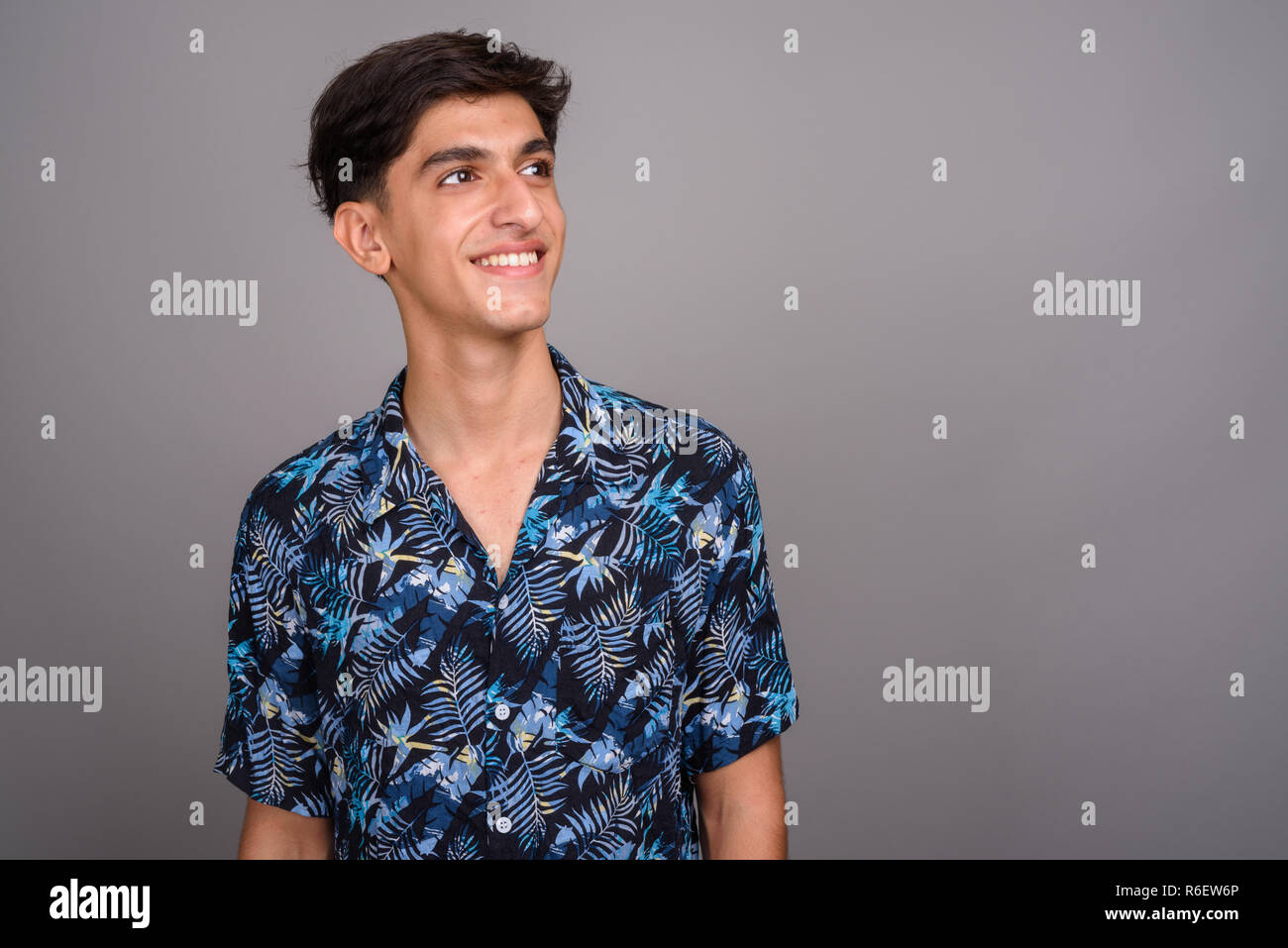 Young happy Persian teenage boy smiling and thinking Stock Photo