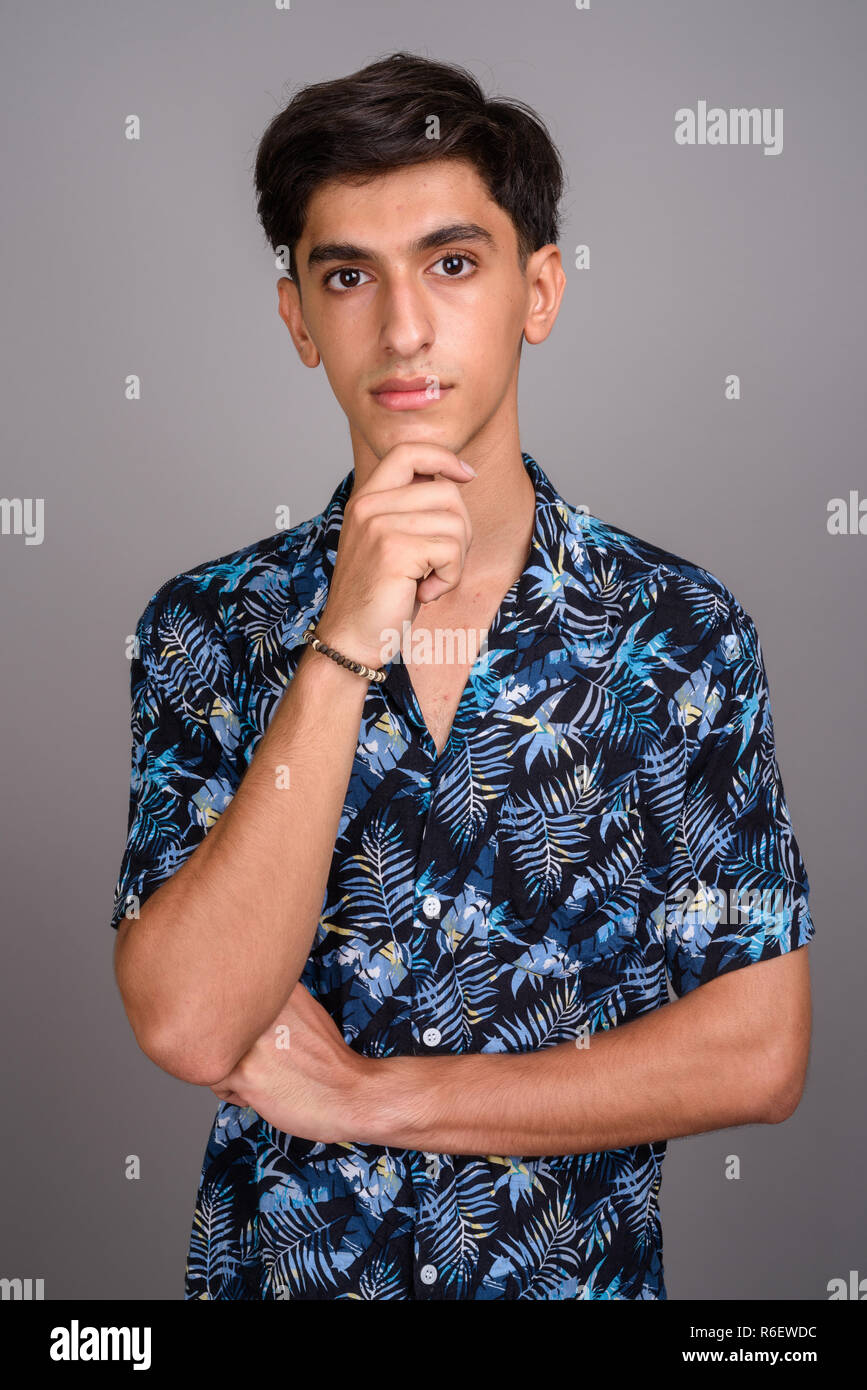 Young handsome Persian teenage boy wearing Hawaiian shirt agains Stock Photo