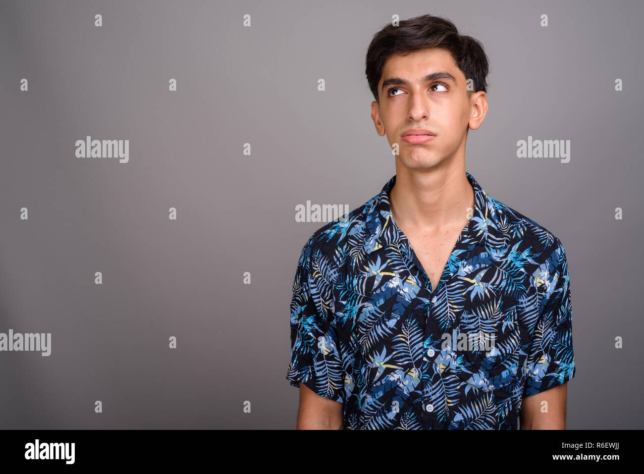 Bored Persian teenage boy wearing Hawaiian shirt agains Stock Photo
