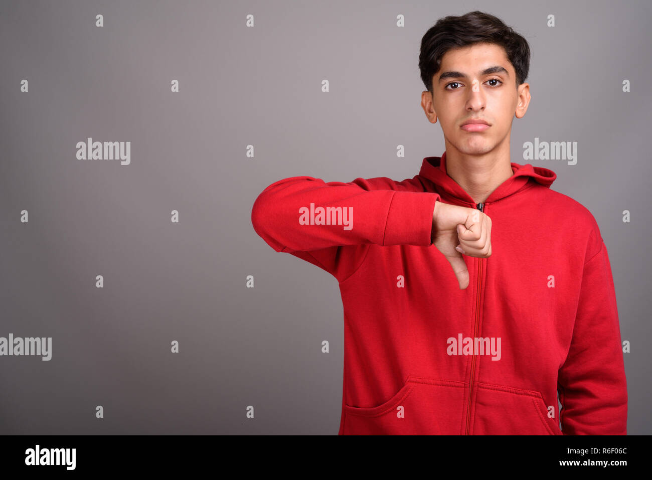 Young handsome Persian teenage boy giving thumb down Stock Photo
