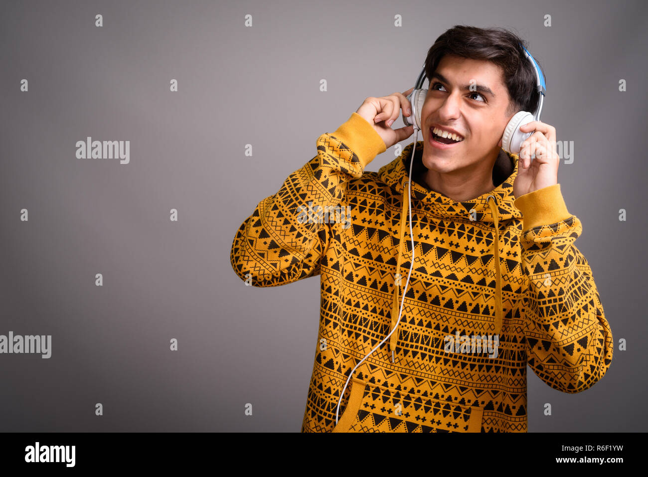 Young happy Persian teenage boy smiling and listening music with headphones Stock Photo