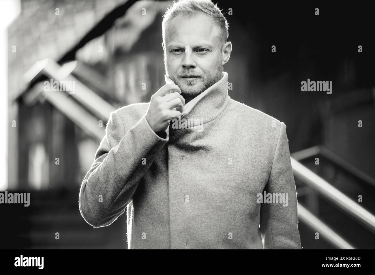 Black and white picture of serious man in coat on street. Stock Photo