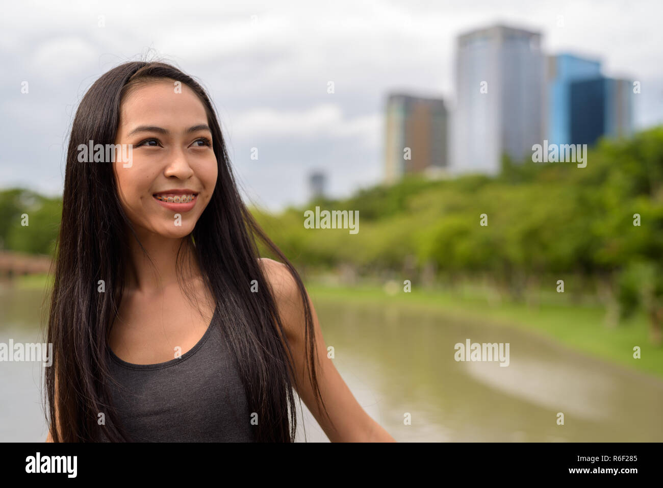 Young beautiful Asian woman smiling and thinking at the park Stock Photo