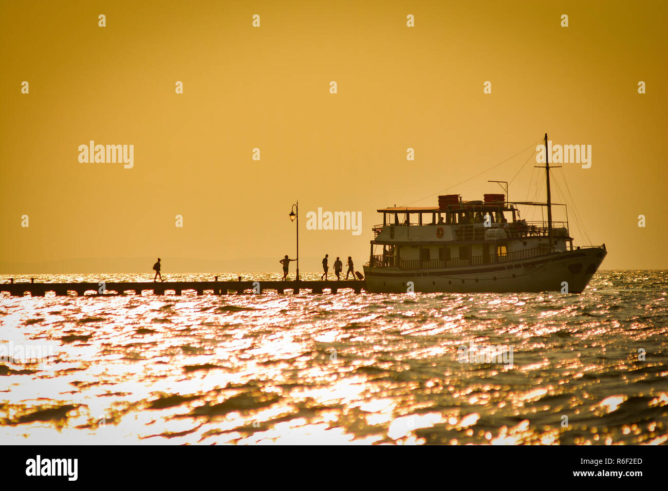 Small boat on the sea pier under golden evening sun Stock Photo