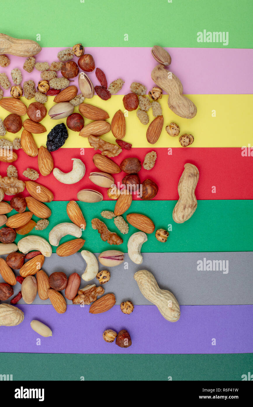 Assorted nuts scattered on a colorful paper background top view Stock Photo