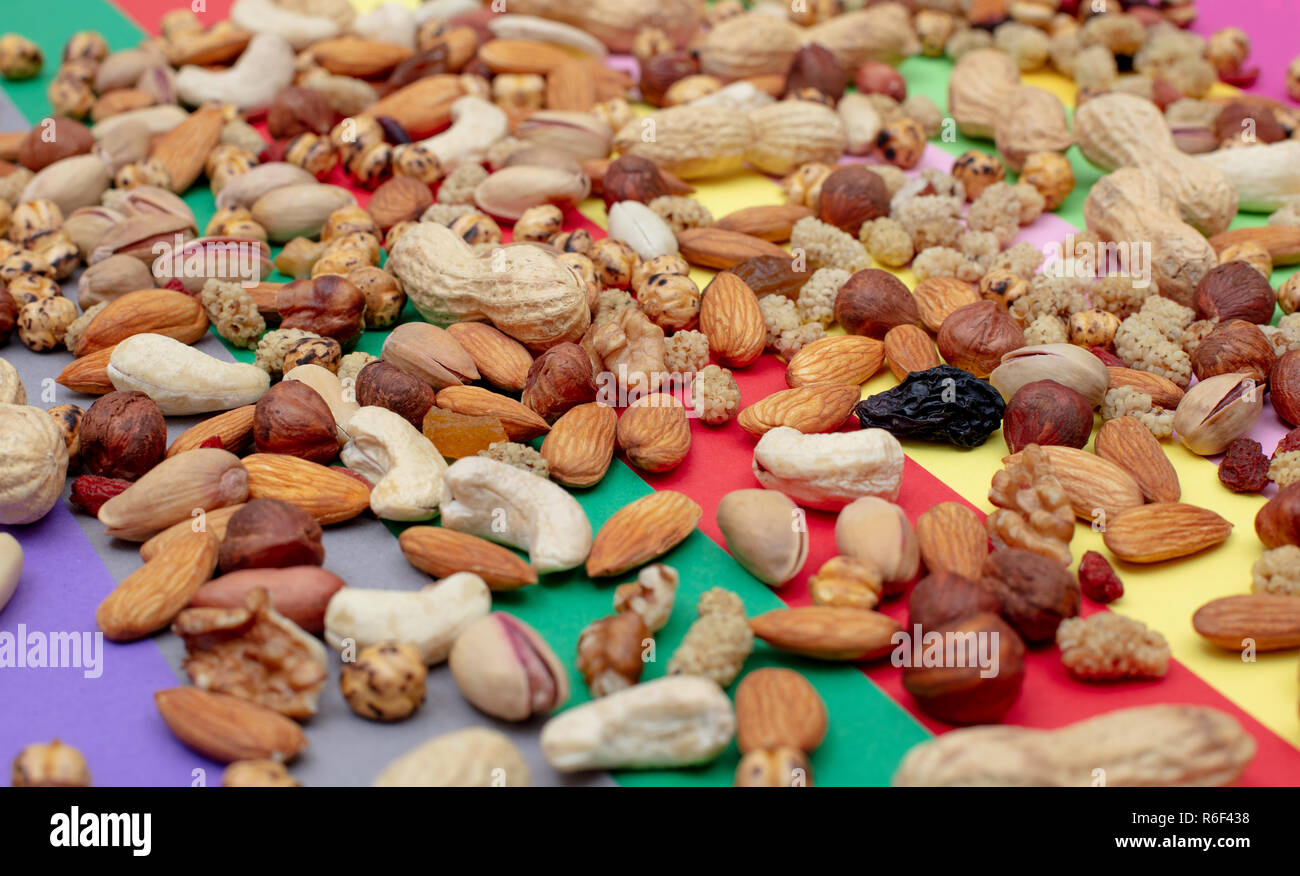 Assorted nuts scattered on a colorful paper background High angle view Stock Photo