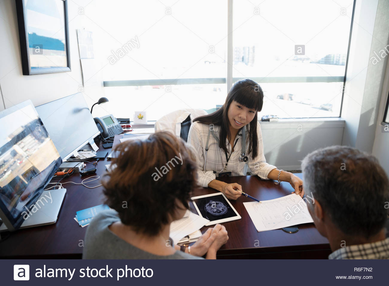 Female doctor discussing test results with mature couple in doctor s office Stock Photo