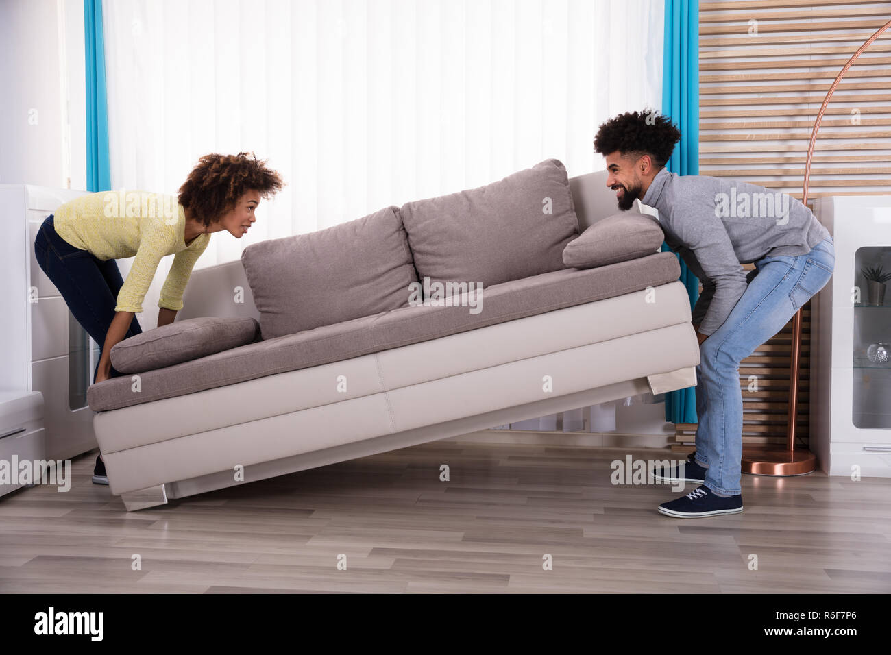 Couple Lifting Sofa In Living Room Stock Photo Alamy