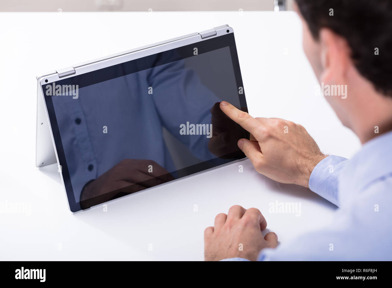 Man Touching Hybrid Laptop Screen With Finger Stock Photo