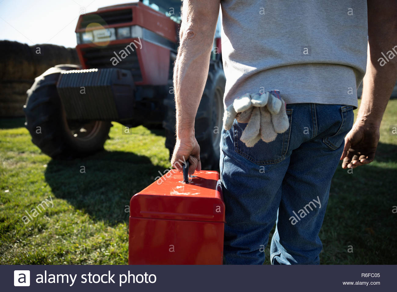 Male farmer carrying toolbox toward tractor on farm Stock Photo Alamy