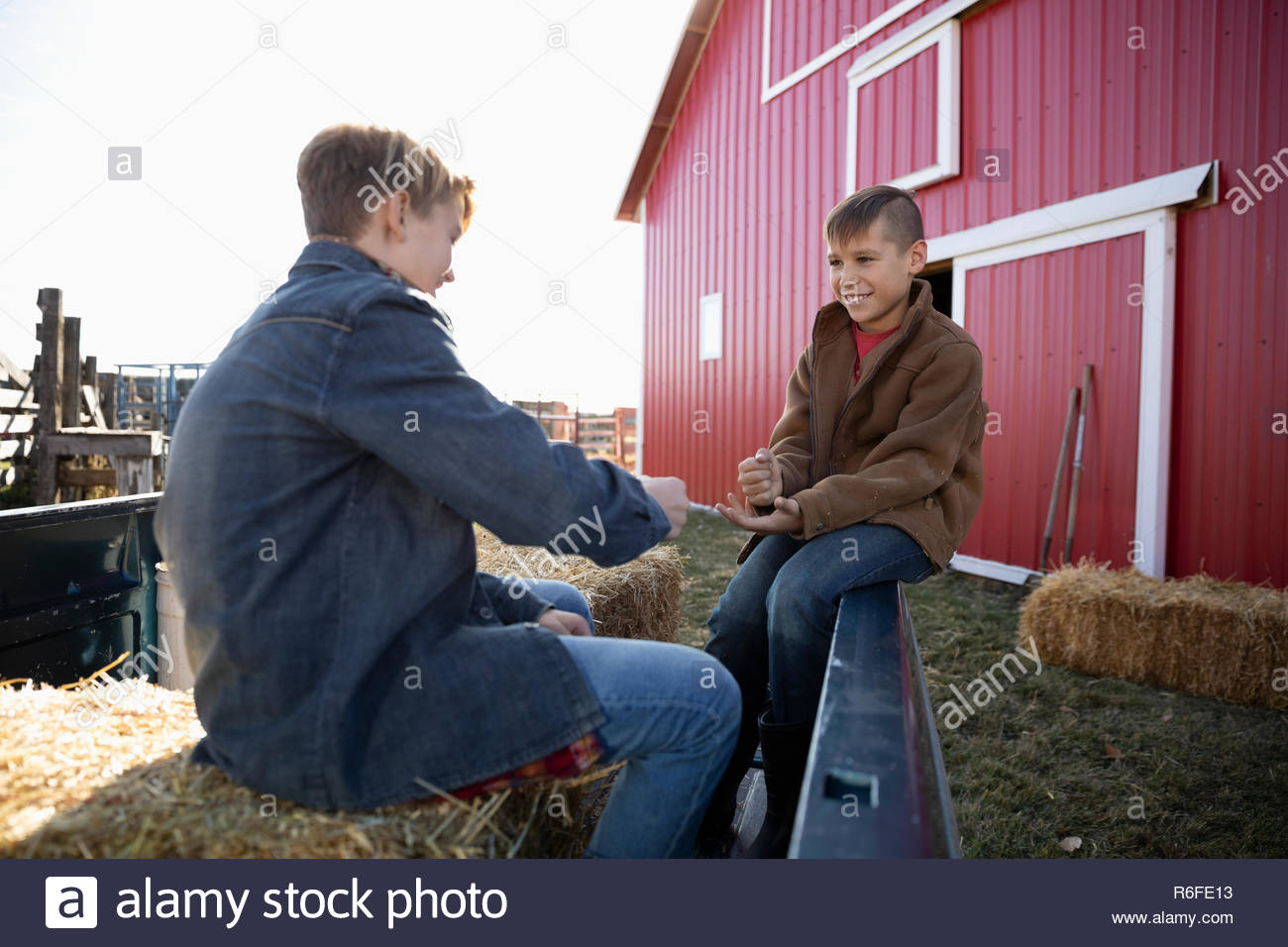 Brothers playing paper rock scissors outside barn on farm Stock Photo
