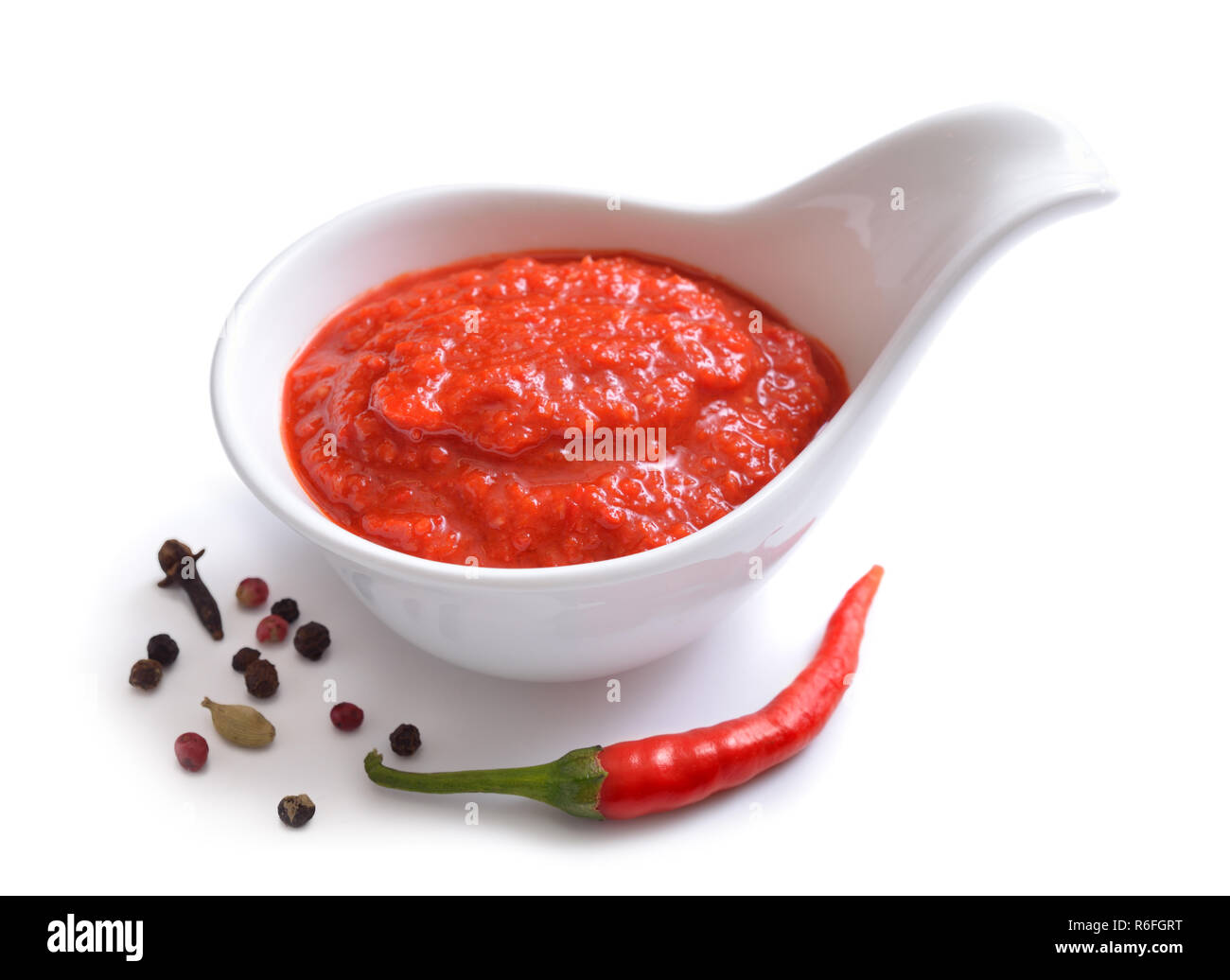 Red chili sauce in the sauce boat. With pepper. Isolated on white