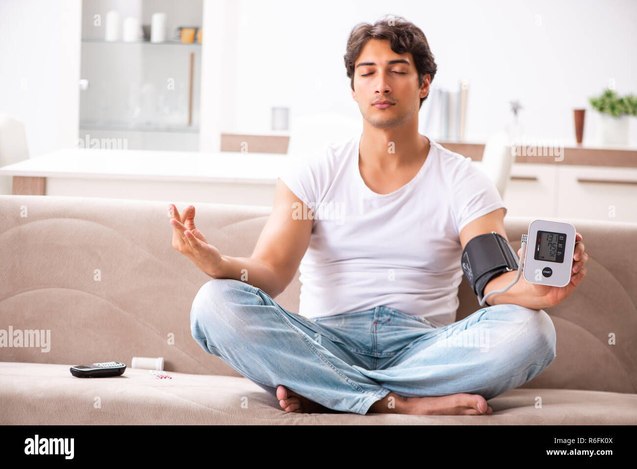 Young man measuring blood pressure at home Stock Photo - Alamy