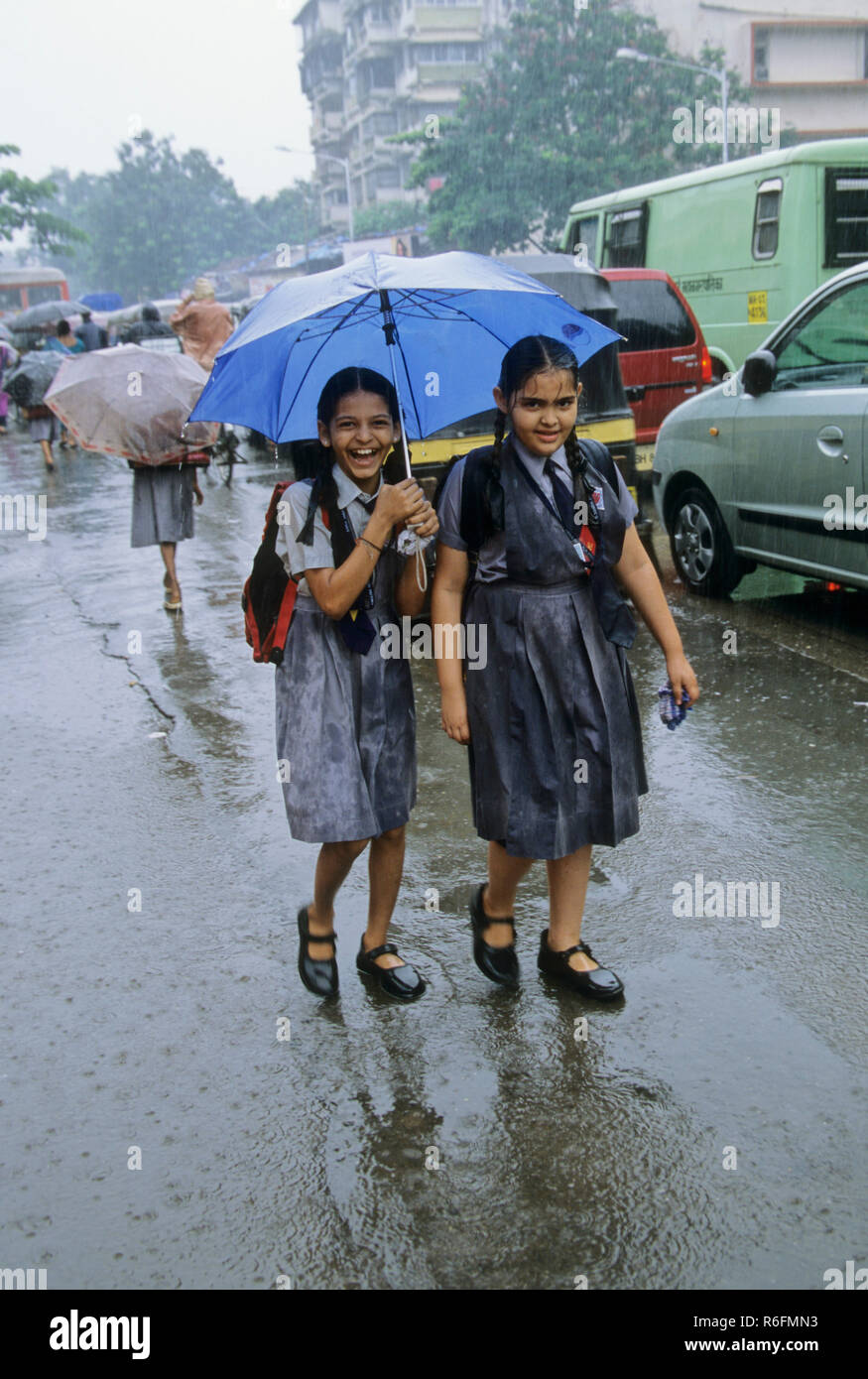 school Girls holding umbrella and walking in rainy day, monsoon, bombay