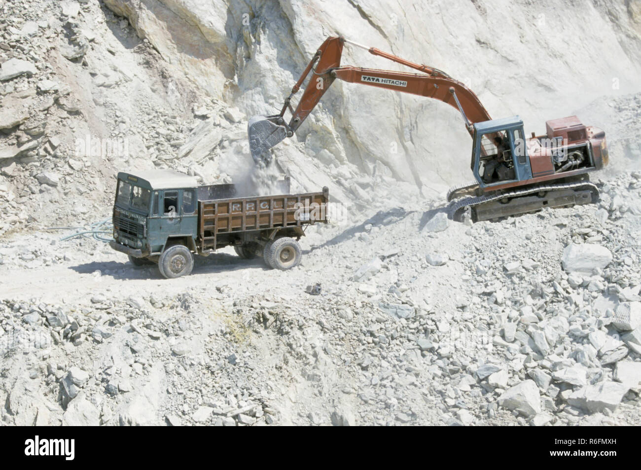 Shovels of Backhoe Loader emptying dust in Truck at soapstone mines