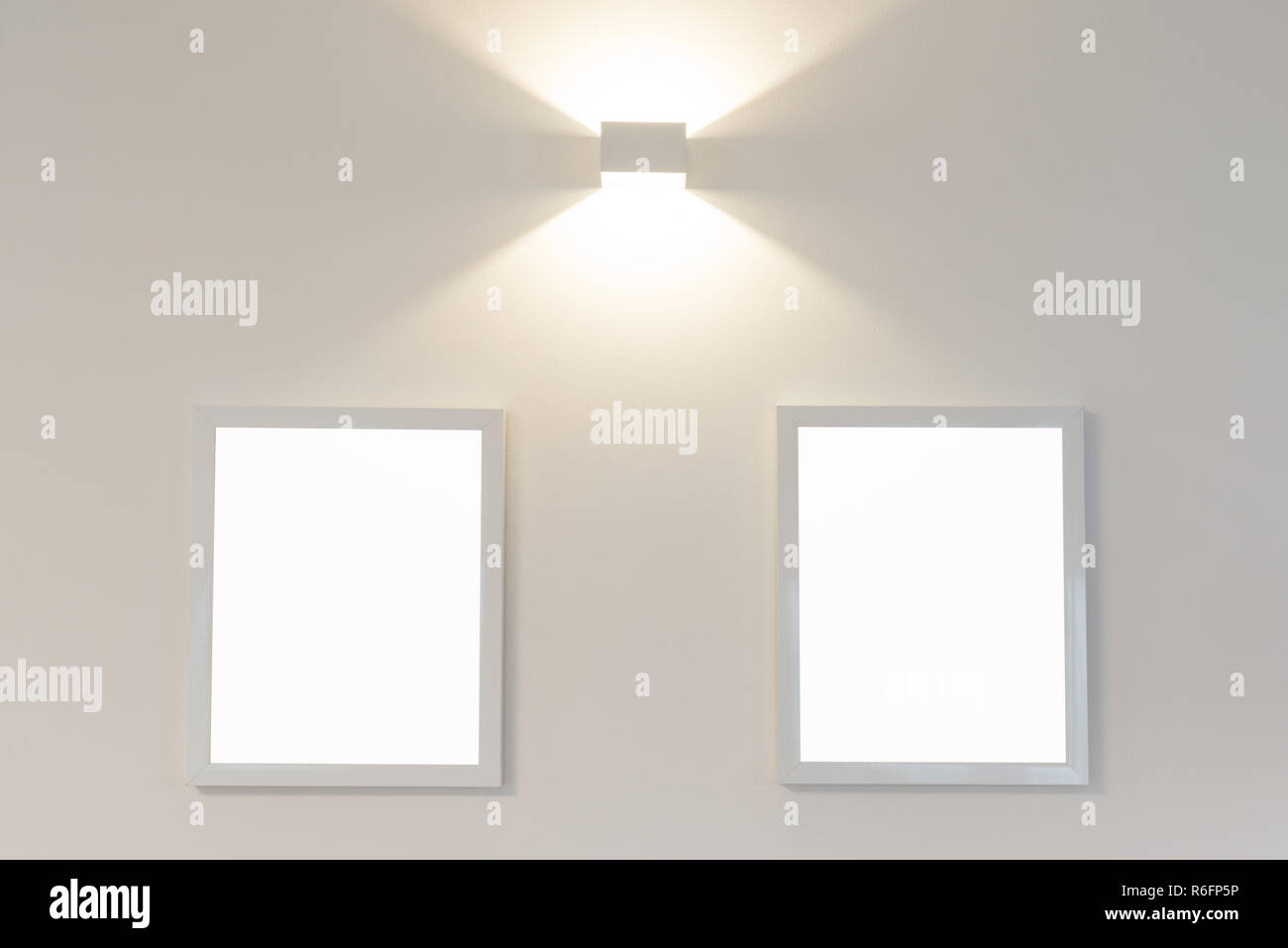 Two blank picture frames on wall with light Stock Photo