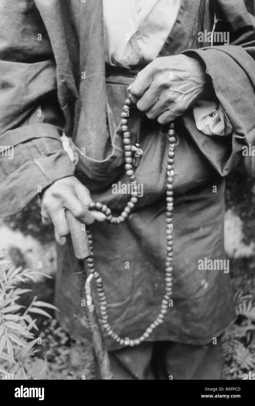Buddhist person chanting on holy beads, India, old vintage 1900s picture Stock Photo