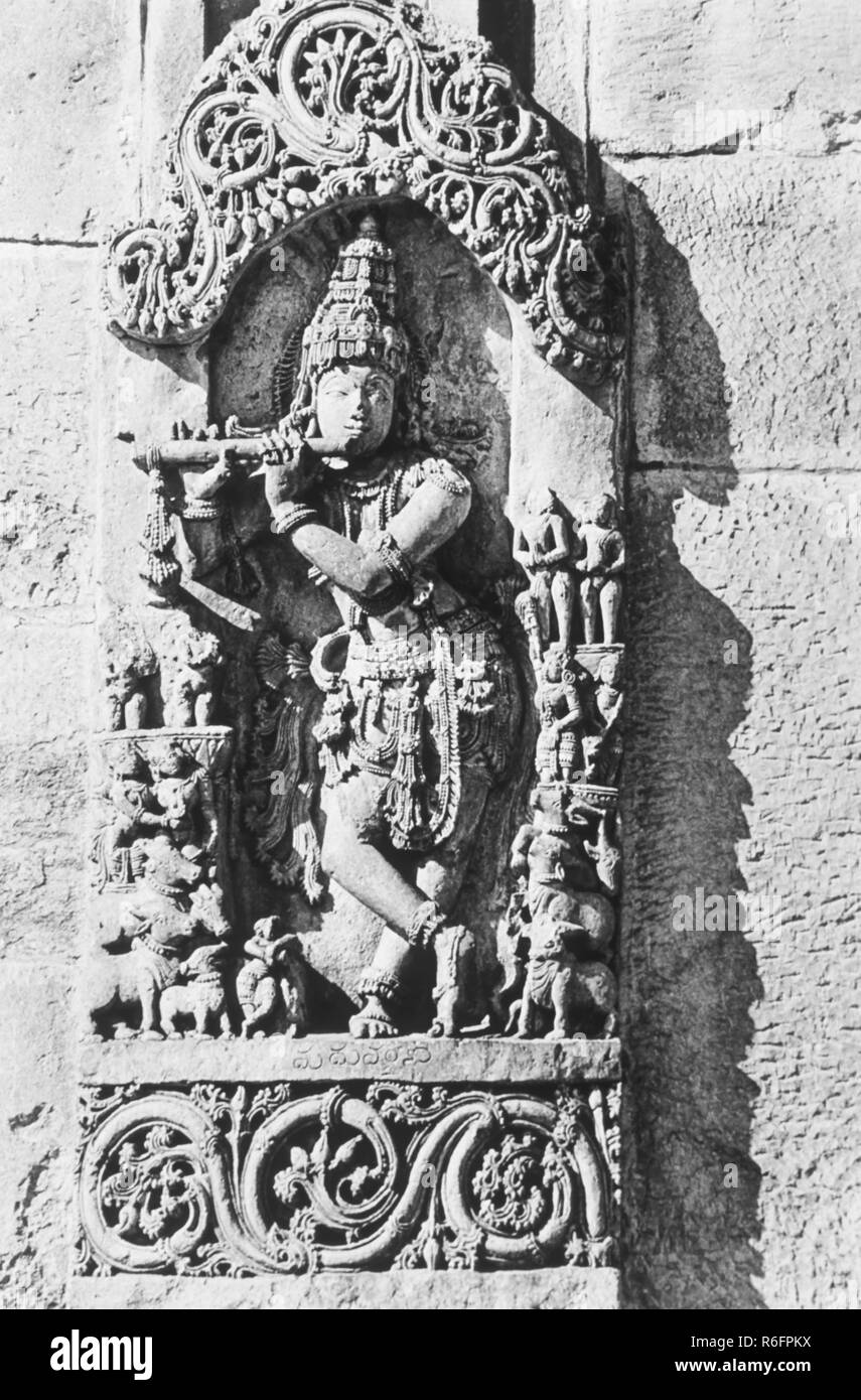 Lord Krishna playing musical instrument flute sculpture, wall relief, India, old vintage 1900s picture Stock Photo