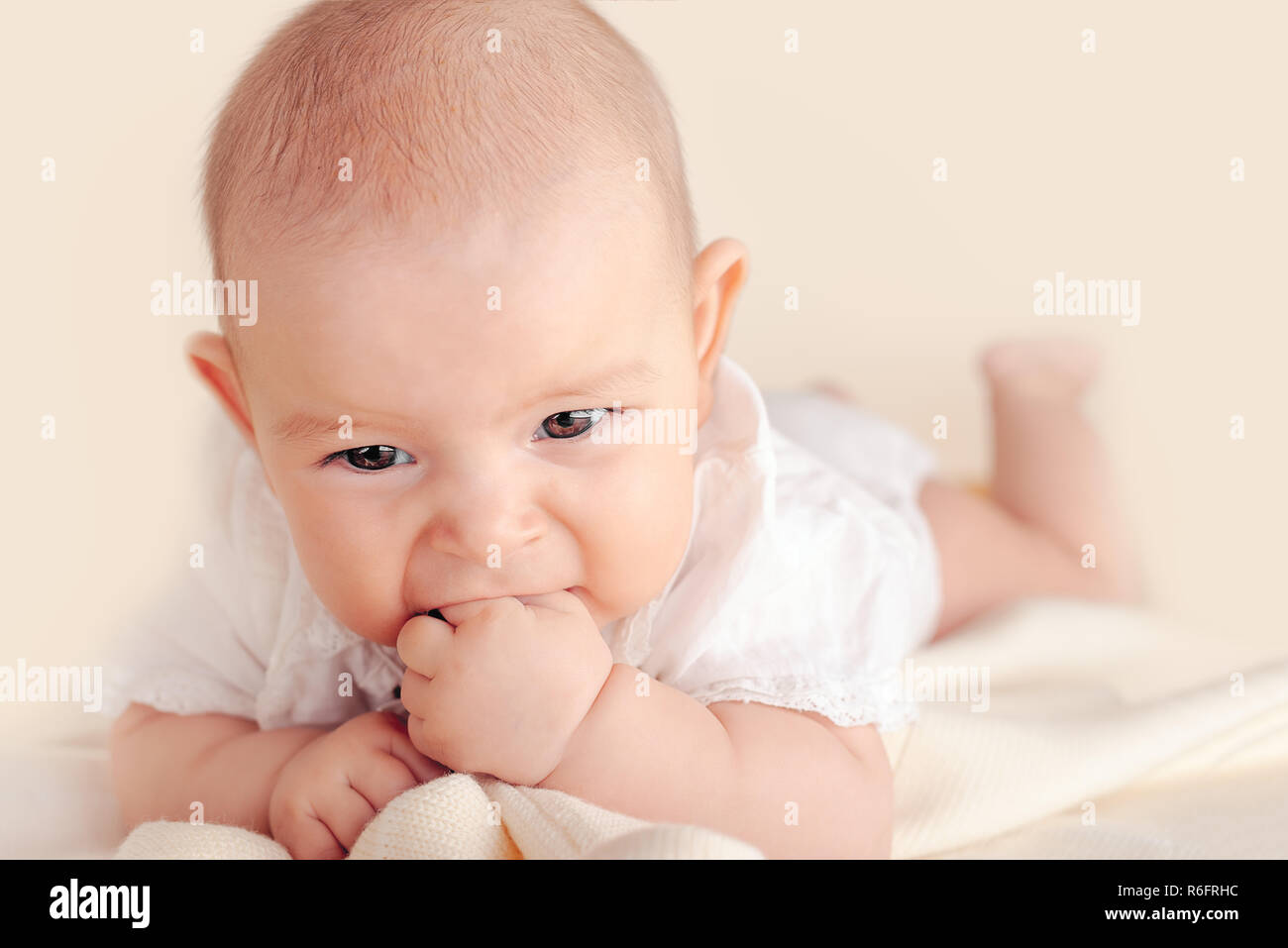 Small cute funny baby infant teething with face expression hands and