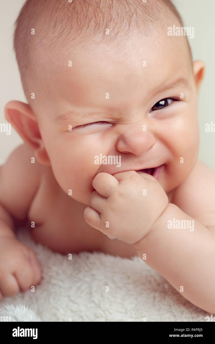 Small cute funny baby infant teething with face expression hands and  fingers in mouth sore gums soothe Stock Photo - Alamy