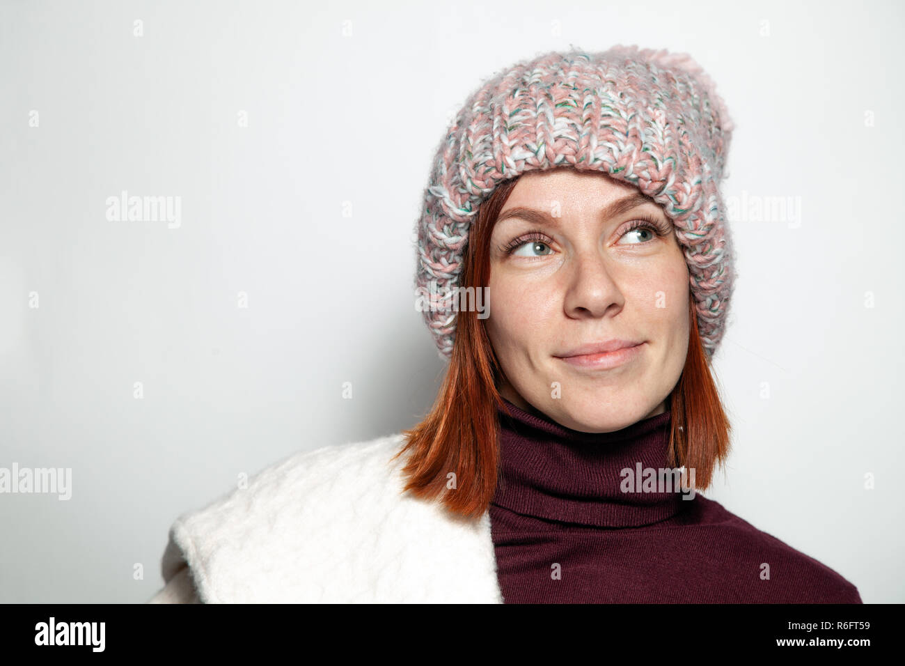 Isolated Portrait Of Beautiful Young Redhead Girl With Green Eyes White And Purple Sweater And Pink Knitted Hat With Pompon Dressed Sideways Smiling O Isolated Portrait Of Beautiful Young Redhead Girl With Green Eyes White And Purple Sweater And Pink Knitted Hat With Pompon Dressed Sideways Smiling O