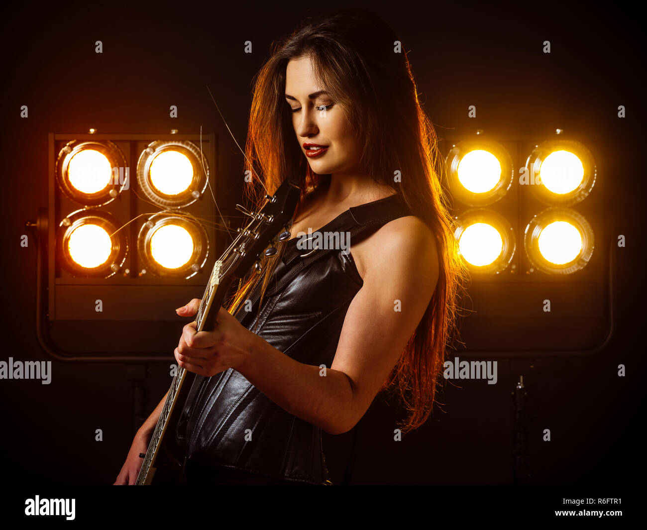 Sexy woman playing electric guitar on stage Stock Photo