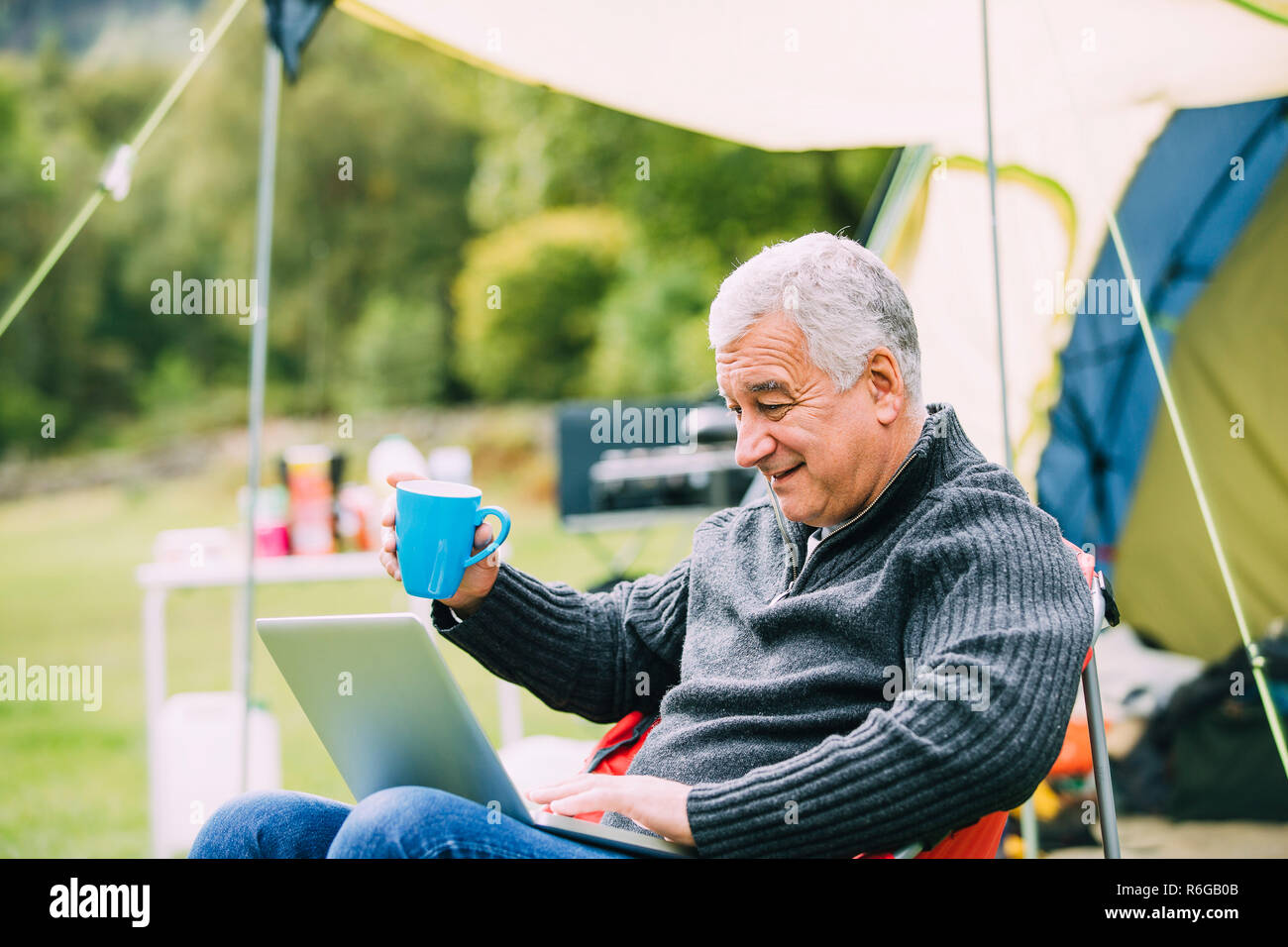 Senior man Using Laptop at Campsite Stock Photo