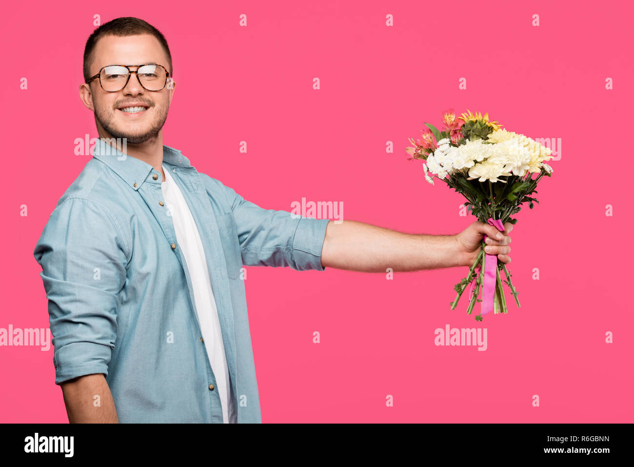 handsome young man holding bouquet of flowers and smiling at camera ...